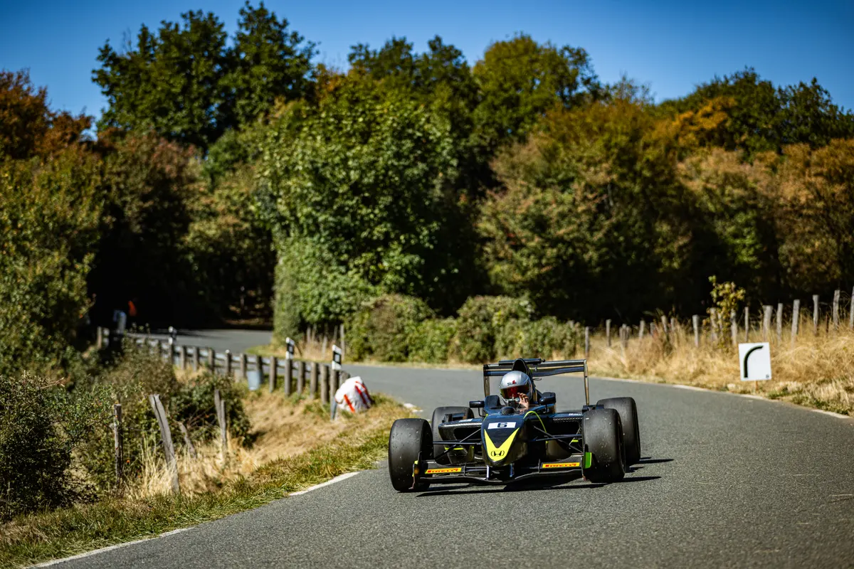 Autre monoplace noire avec casque gris en montée sur route de montagne