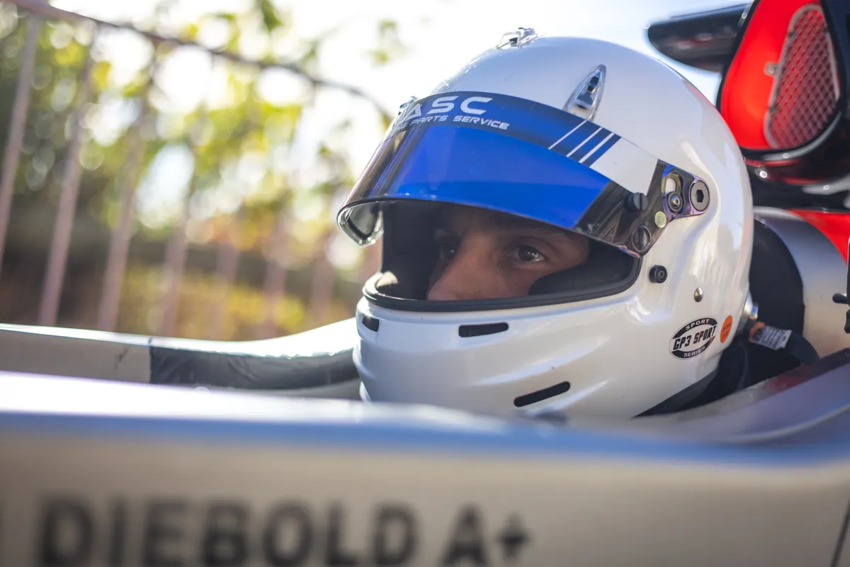 Pilote debout à côté d'une monoplace noire en zone de parc fermé