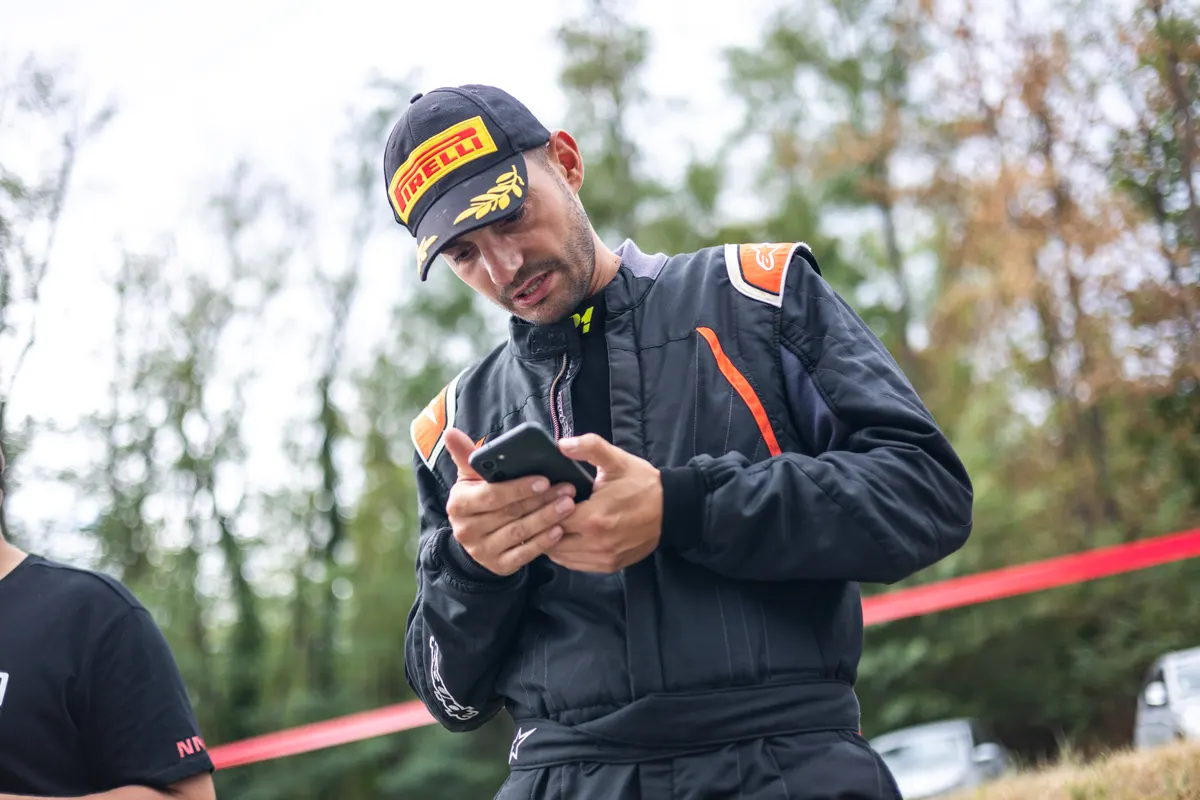 David Diebold, en combinaison, consulte son téléphone. Turckheim 2026.